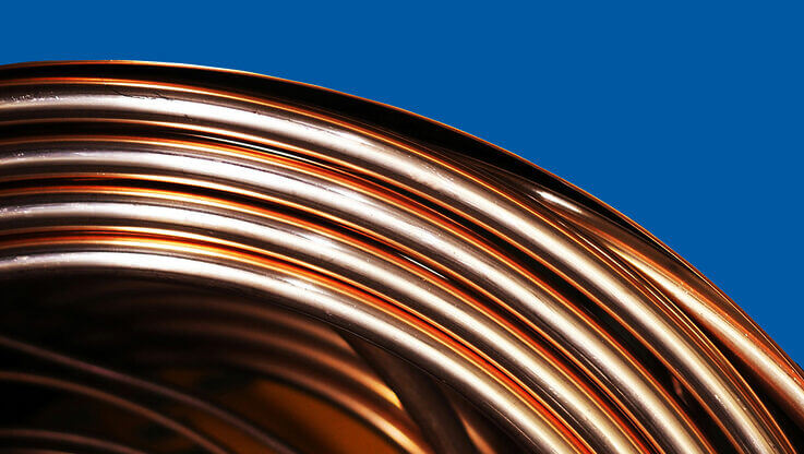 a close up of a reel of copper tubing on a plain blue background