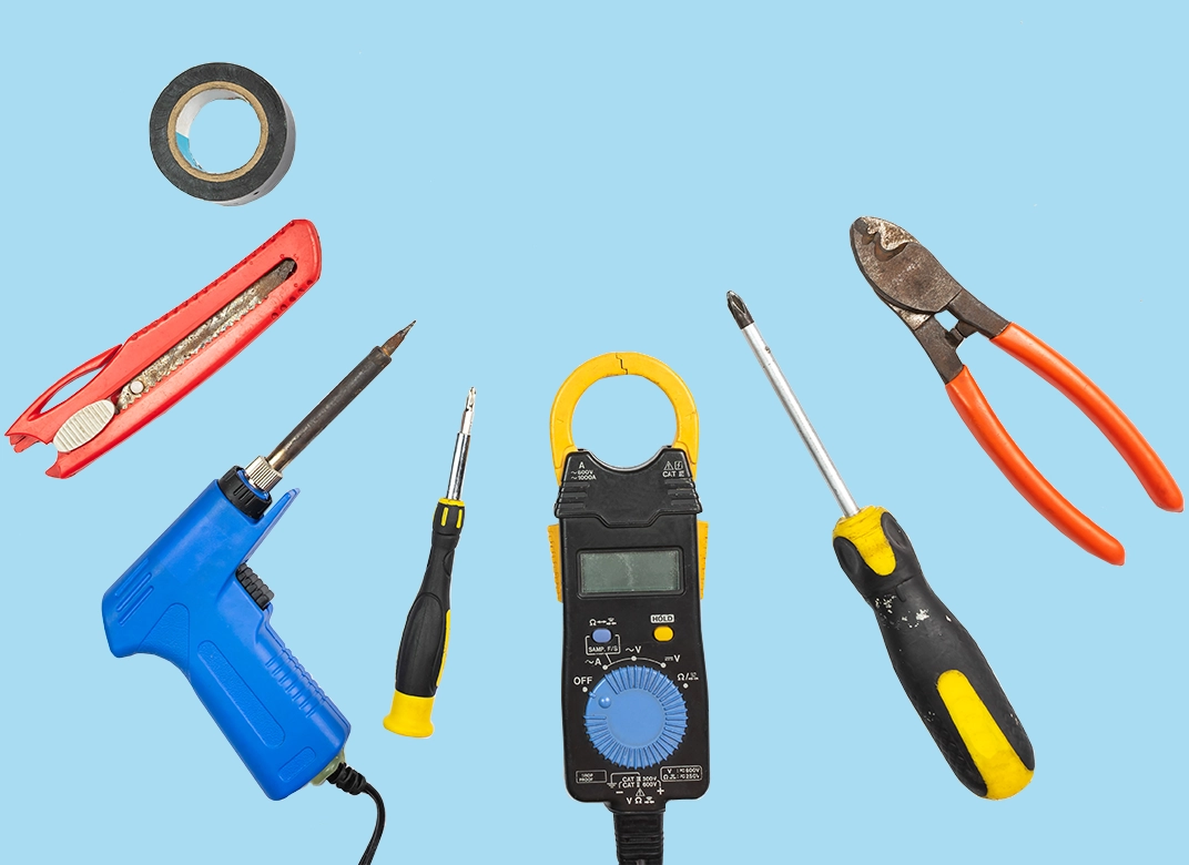 various electrical repair hand tools laid out in a semi circle on a blue background