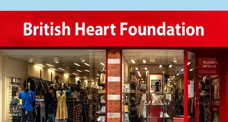 Shop front window of a red shop with a 'British Heart Foundation' sign and blue backdrop.