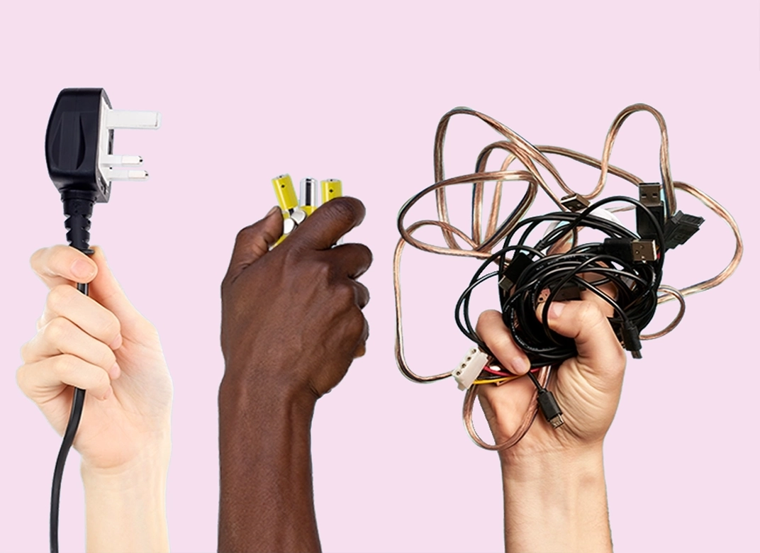 a light skinned hand holding a plug in the air, dark skinned hand holding a battery up in the air a light skinned hand holding a mass of cables up in the air all on a pink background