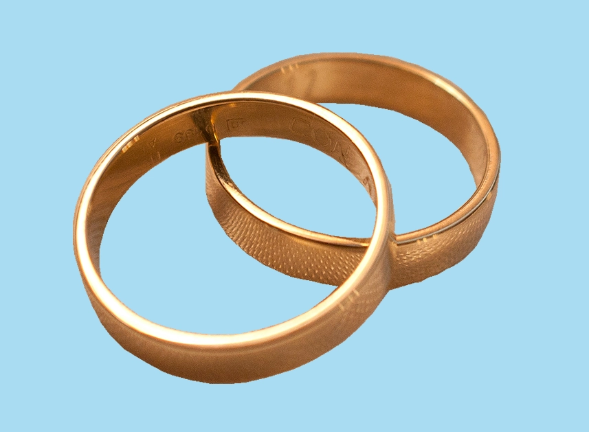 two gold rings one on top of another on a plain blue background