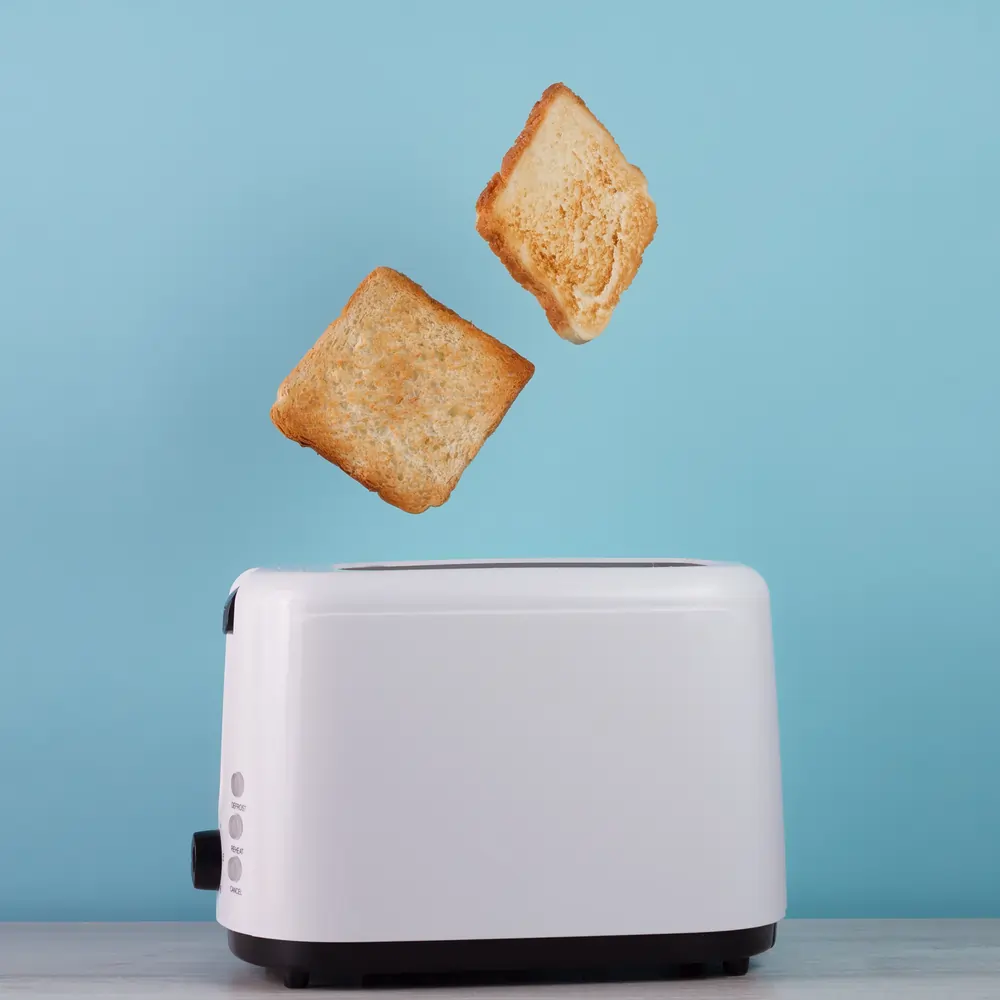 a toaster with two slices of white toast popping out of it in mid air
