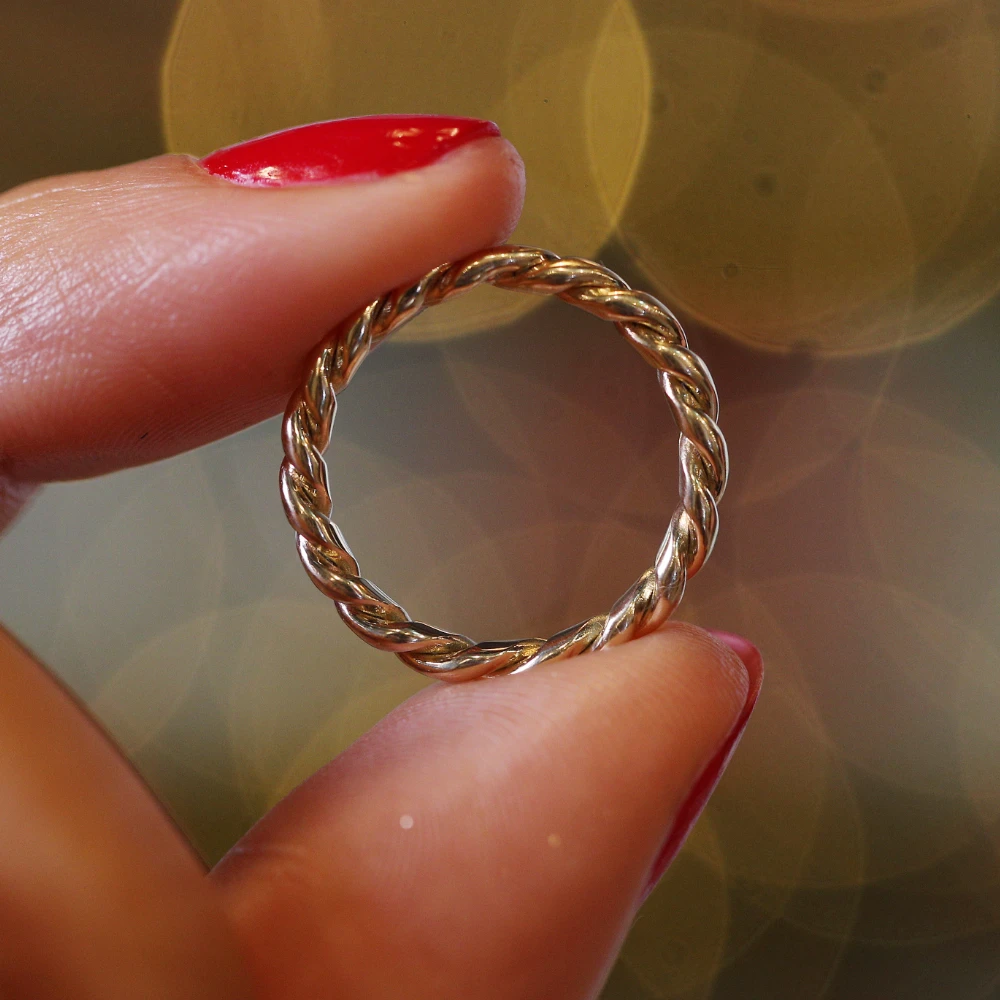 close up of a medium skinned womans fingers with red nail polish holding a ring made by Lylie's from recycled electricals