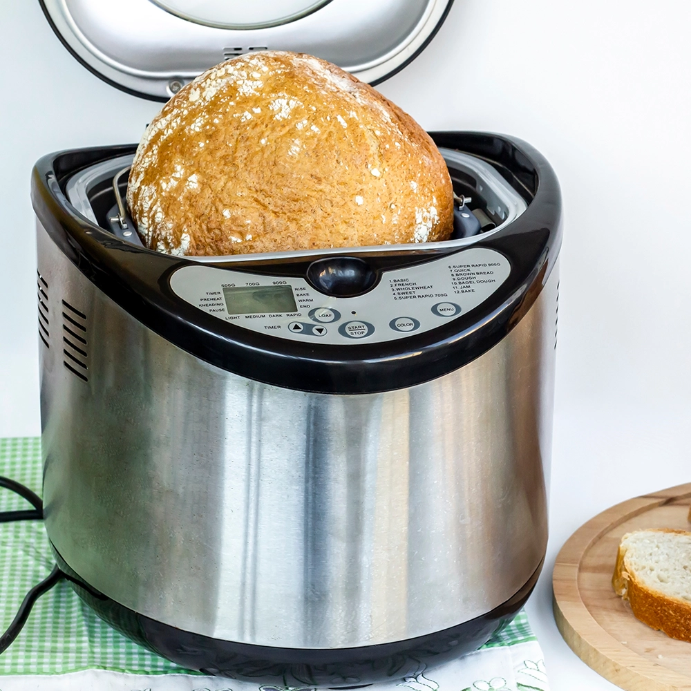 shiny breadmaker with top open and freshly made bread inside