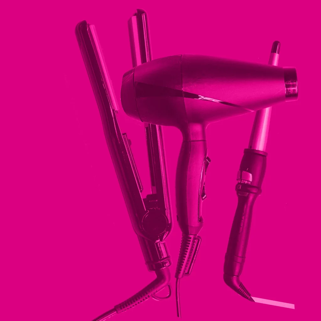 Floating hairdryer, tongs and straighteners in a pink haze against a bright pink backdrop