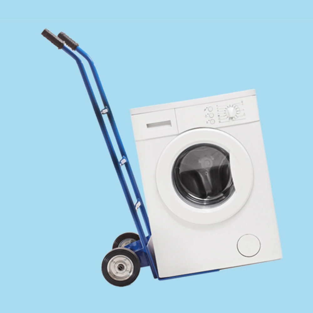 a washing machine on a porter's trolley tilted against a bright blue backdrop