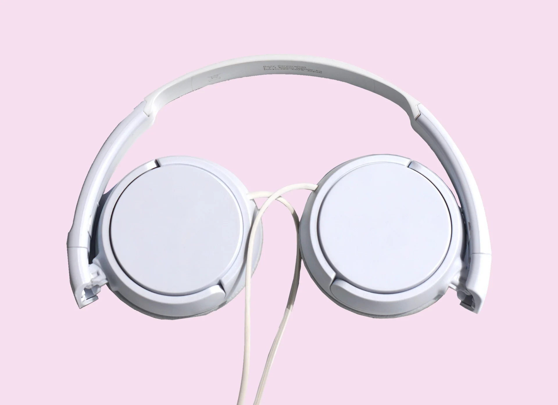 white over-ear heaphones against a pale pink background